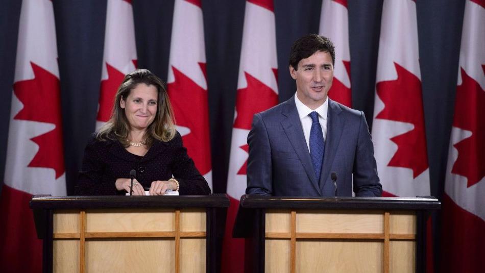 "Justin Trudeau and Chrystia Freeland standing at podiums in front of Canadian flags"