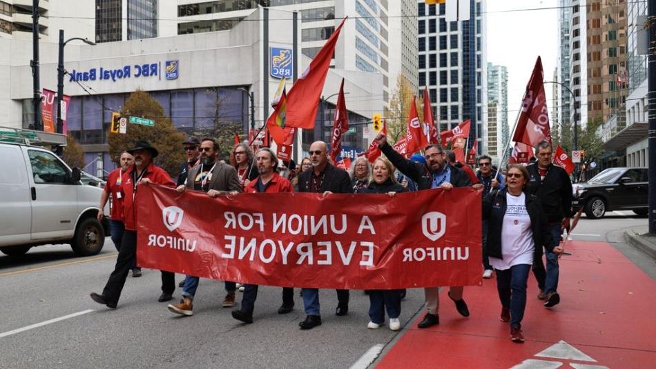 人们举着横幅和横幅在城市街道上游行，横幅上写着uedbet新版官网: a union for all.